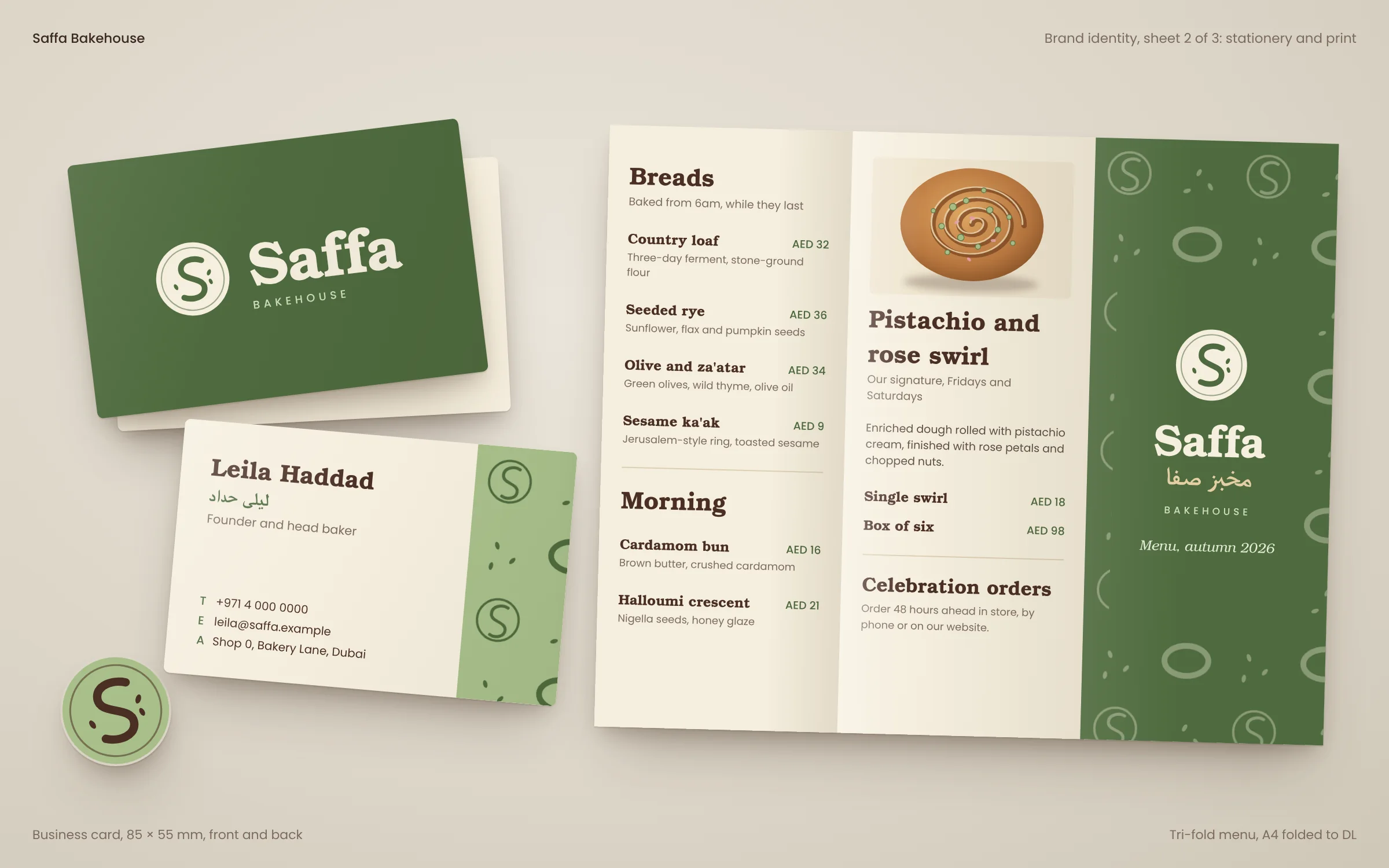 Saffa Bakehouse business cards front and back, a round seal sticker and an open tri-fold menu with breads, prices and a green patterned cover on a neutral surface